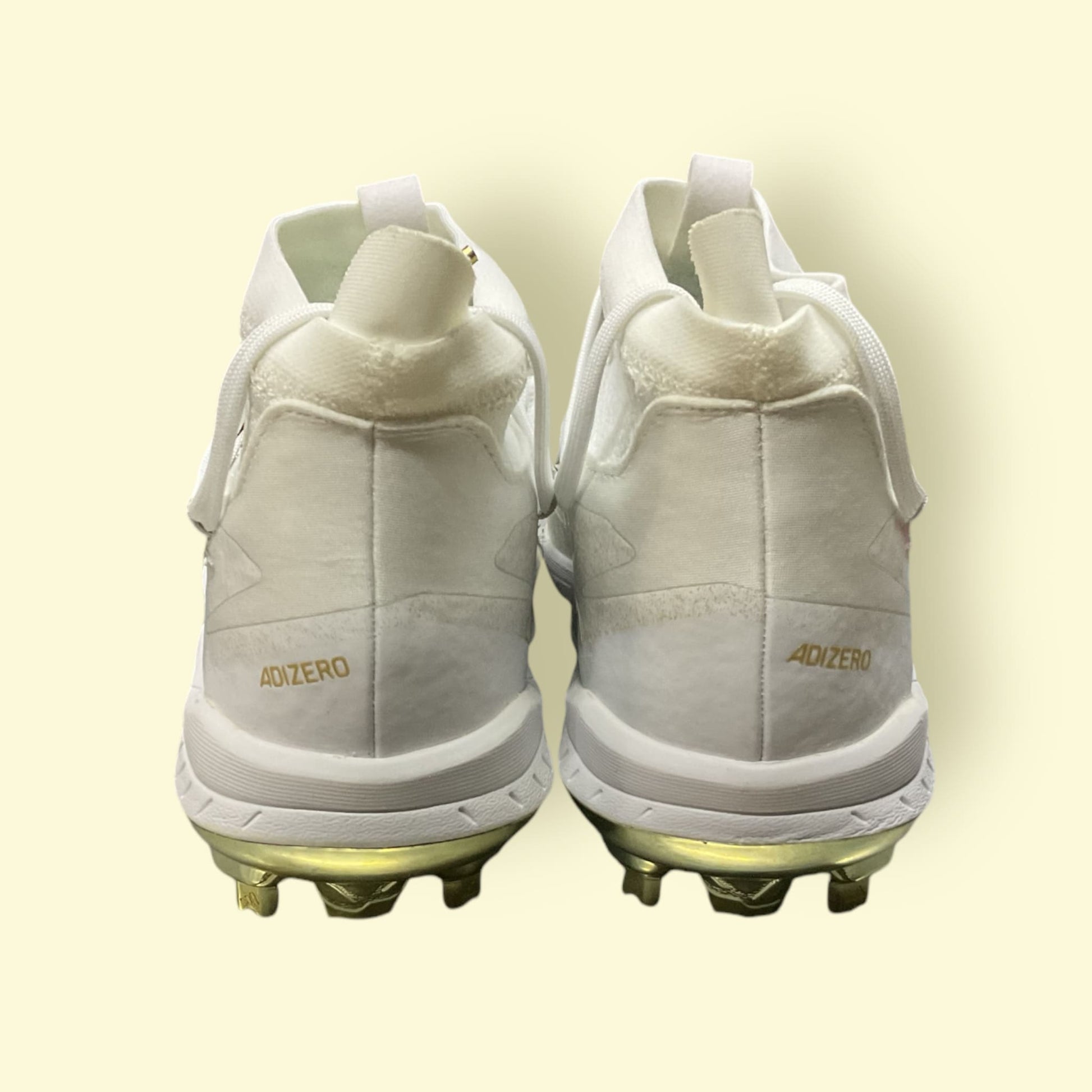 Zapatillas de béisbol Adizero Afterburner 8 NWV en blanco y dorado, ligeras y transpirables, diseñadas para velocidad y tracción óptima en el campo