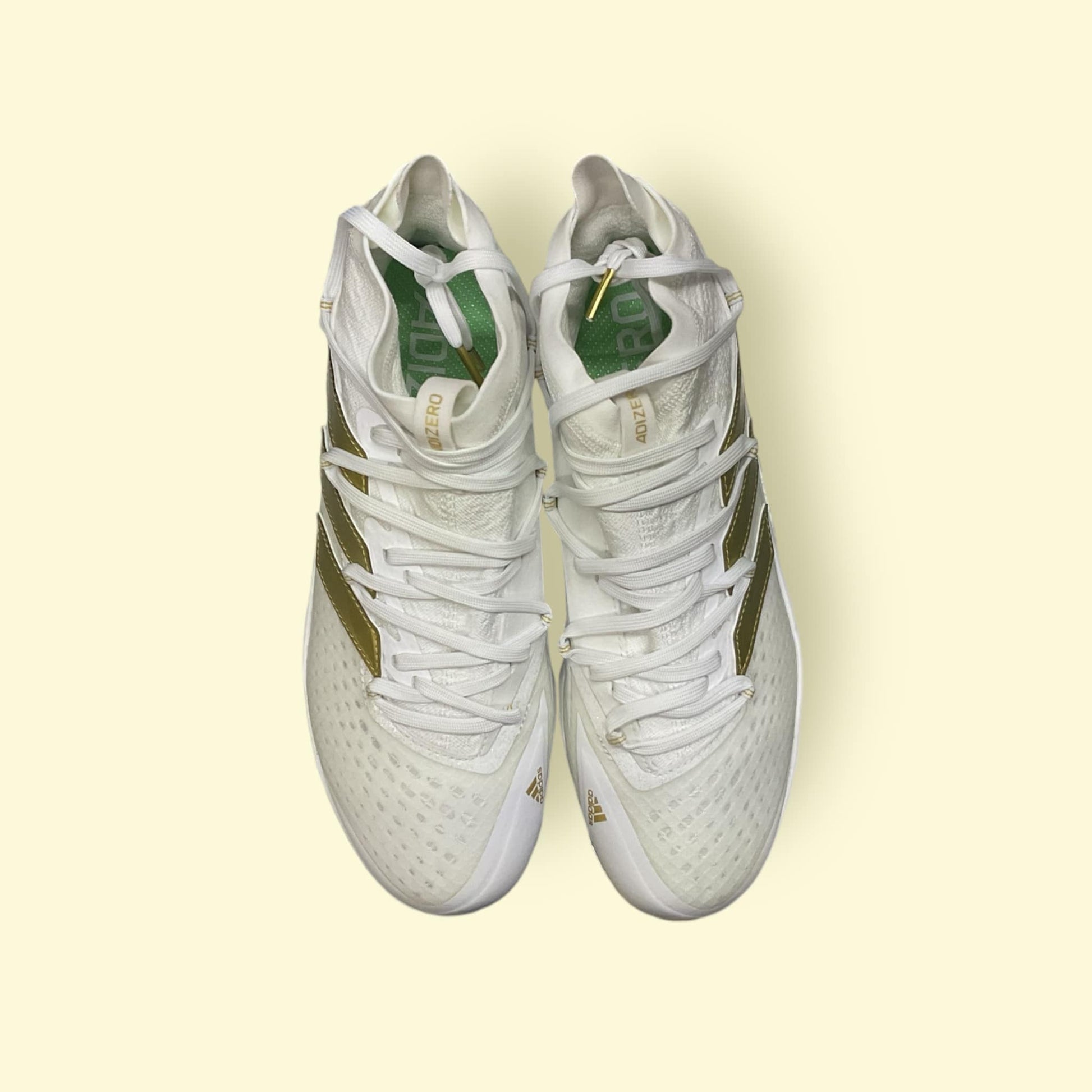 Zapatillas de béisbol Adizero Afterburner 8 NWV en blanco y dorado, ligeras y transpirables, diseñadas para velocidad y tracción óptima en el campo