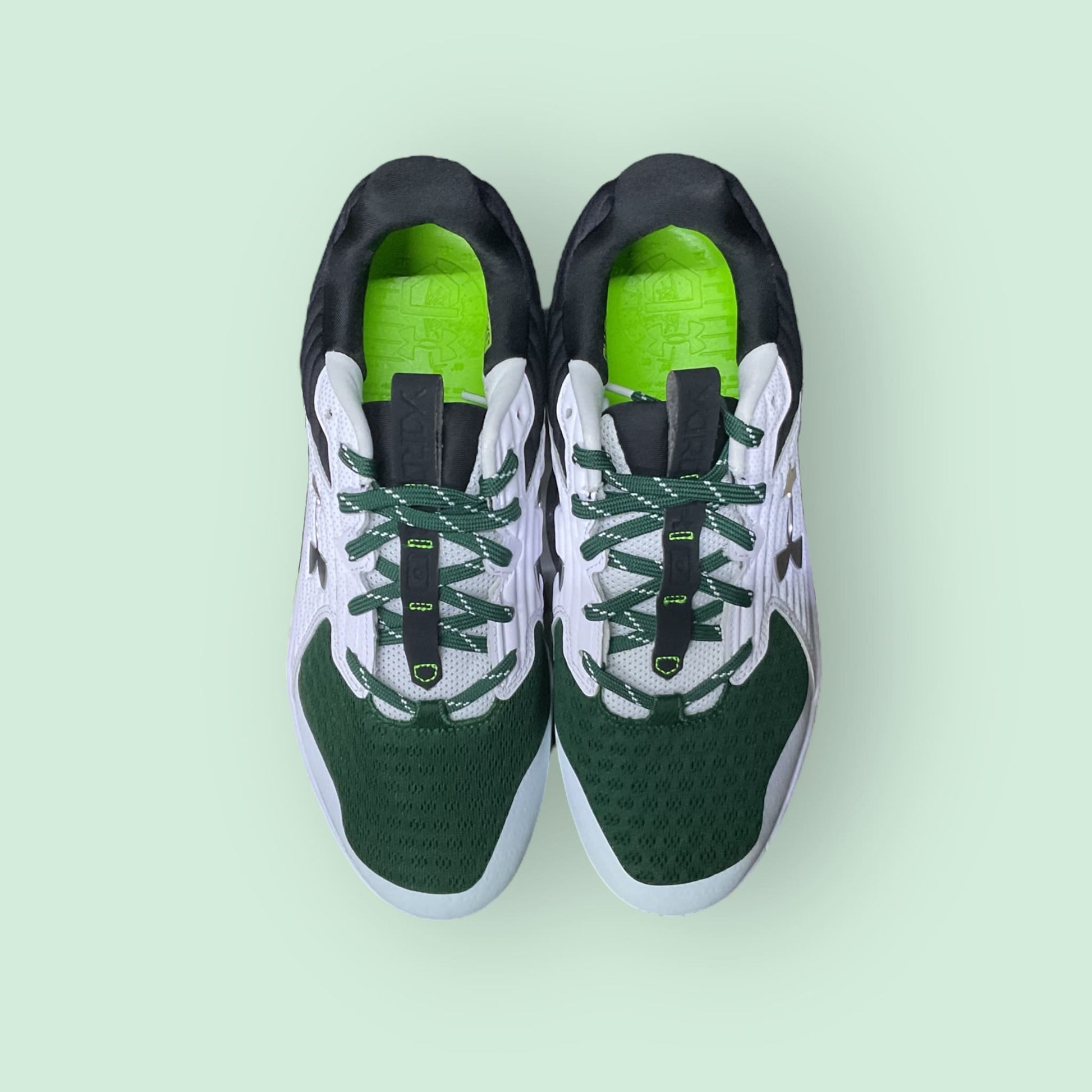 Zapatillas de béisbol UA Yard MT en verde, con suela de tacos y diseño de media altura, ofreciendo estabilidad, comodidad y tracción en el campo