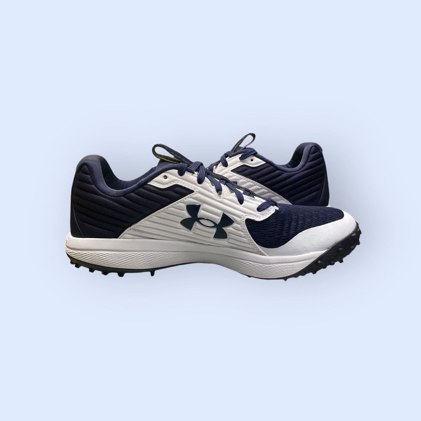 Zapatillas de béisbol UA Yard Turf en blanco y azul, con suela Turf, diseñadas para tracción y comodidad en superficies artificiales durante el entrenamiento
