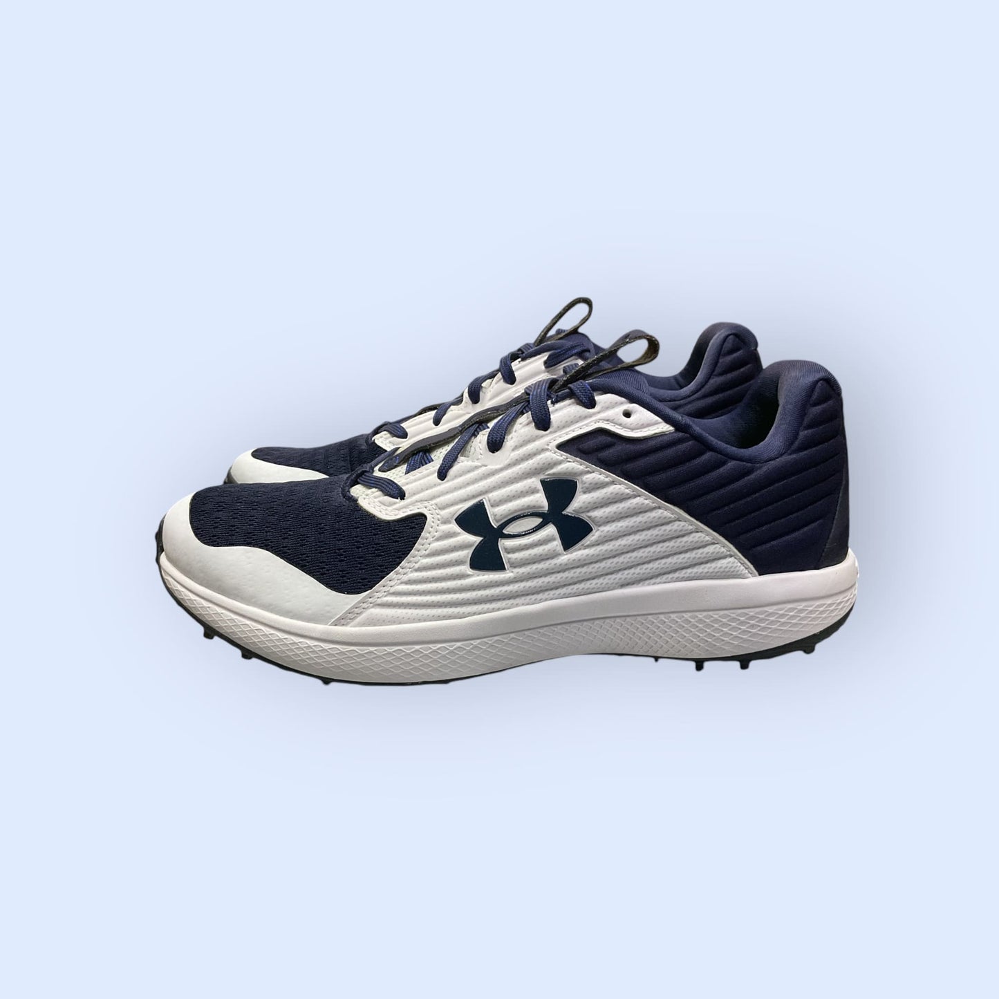 Zapatillas de béisbol UA Yard Turf en blanco y azul, con suela Turf, diseñadas para tracción y comodidad en superficies artificiales durante el entrenamiento