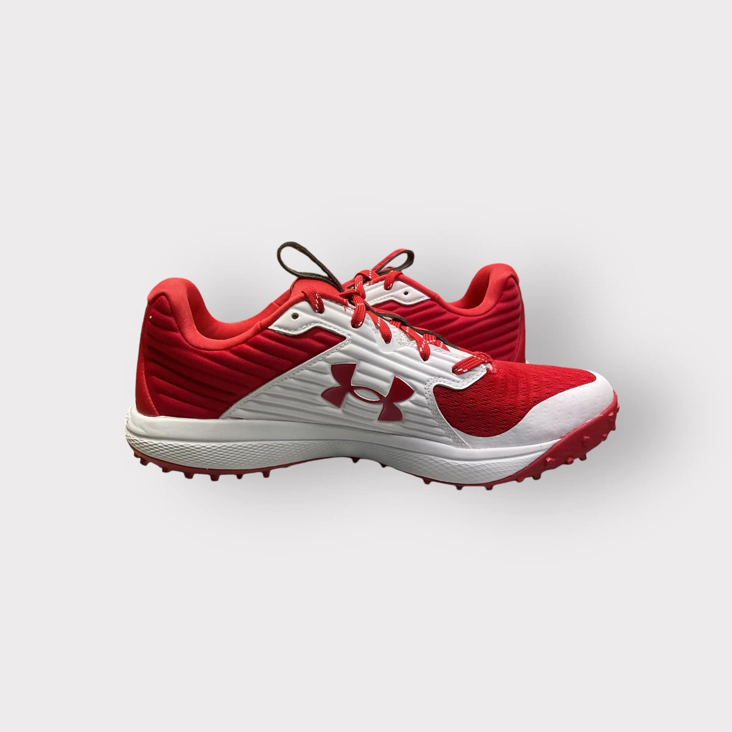 Zapatillas de béisbol UA Yard Turf en blanco y rojo, con suela Turf, diseñadas para entrenamiento con gran tracción y comodidad en superficies artificiales