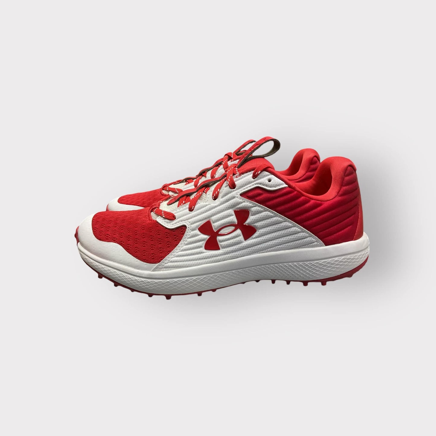 Zapatillas de béisbol UA Yard Turf en blanco y rojo, con suela Turf, diseñadas para entrenamiento con gran tracción y comodidad en superficies artificiales
