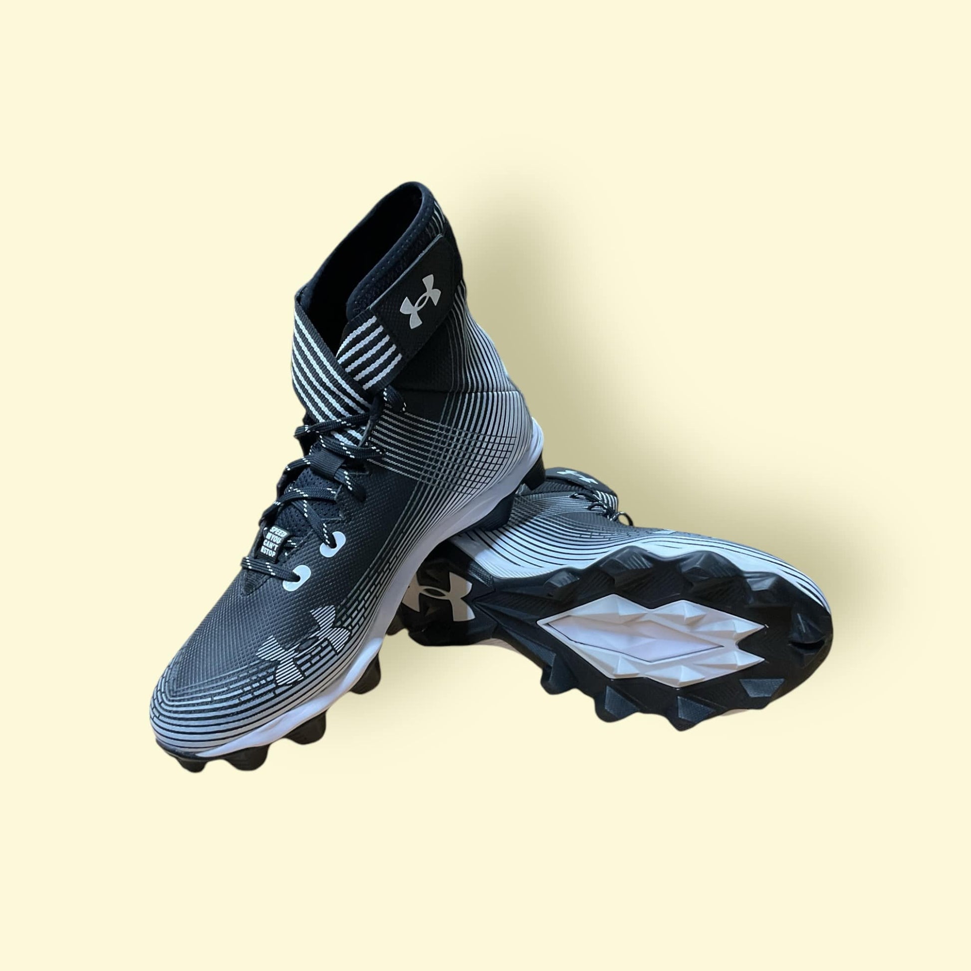 Tacos deportivos UA Highlight Franchise negros para béisbol y fútbol, con soporte en tobillo y suela de tracción.