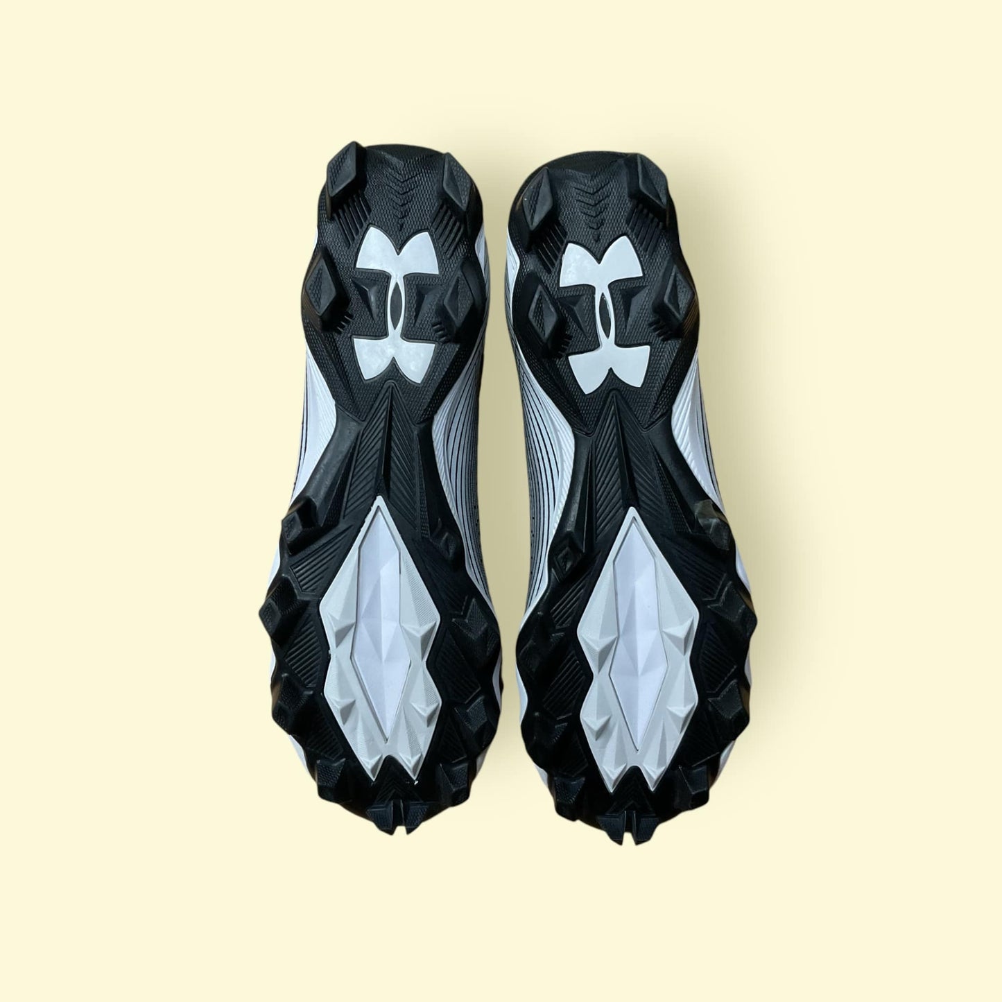 Tacos deportivos UA Highlight Franchise negros para béisbol y fútbol, con soporte en tobillo y suela de tracción.