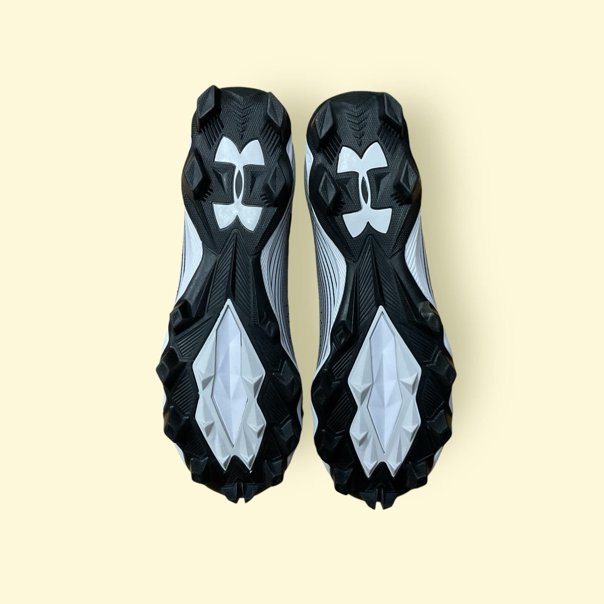 Tacos deportivos UA Highlight Franchise negros para béisbol y fútbol, con soporte en tobillo y suela de tracción.