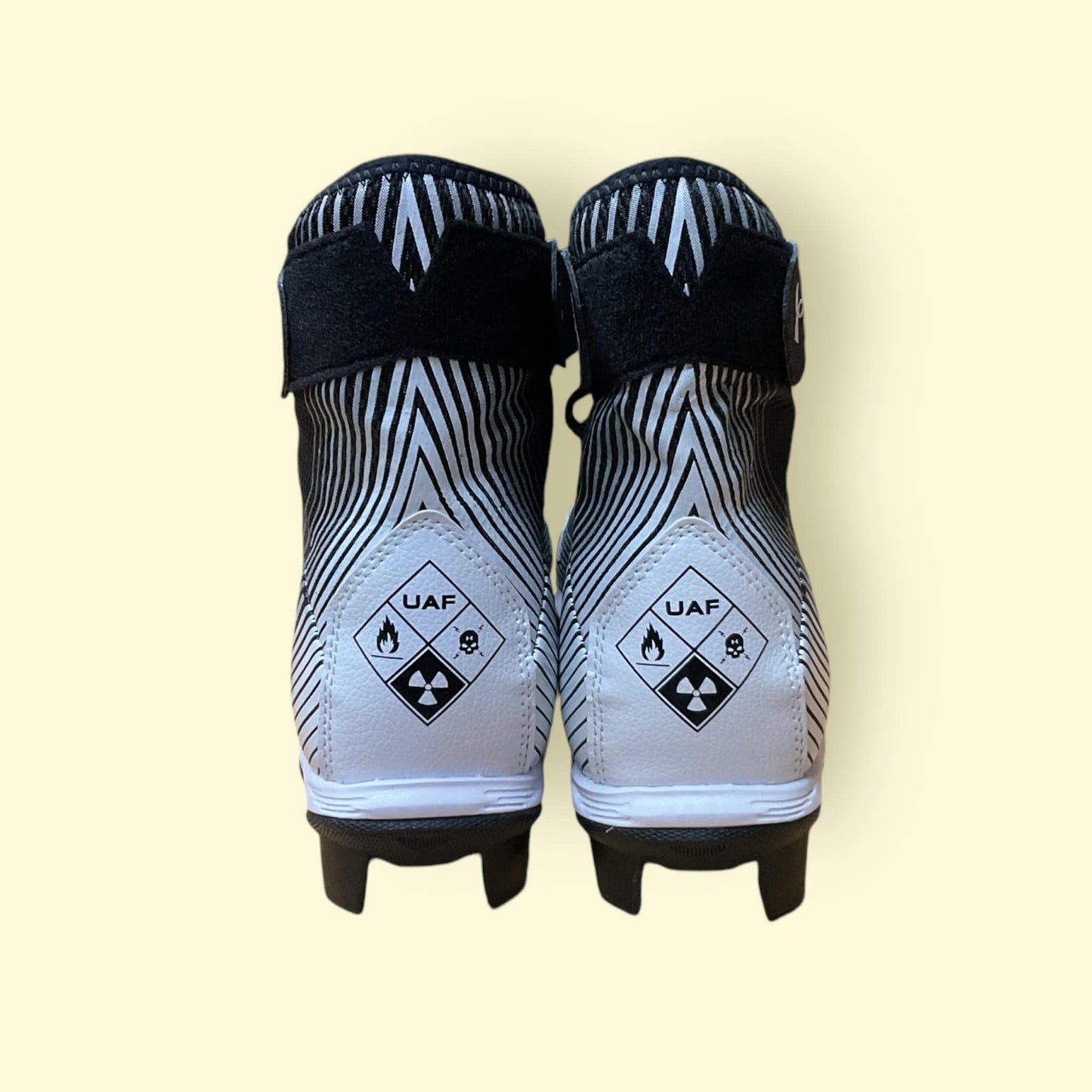 Tacos deportivos UA Highlight Franchise negros para béisbol y fútbol, con soporte en tobillo y suela de tracción.