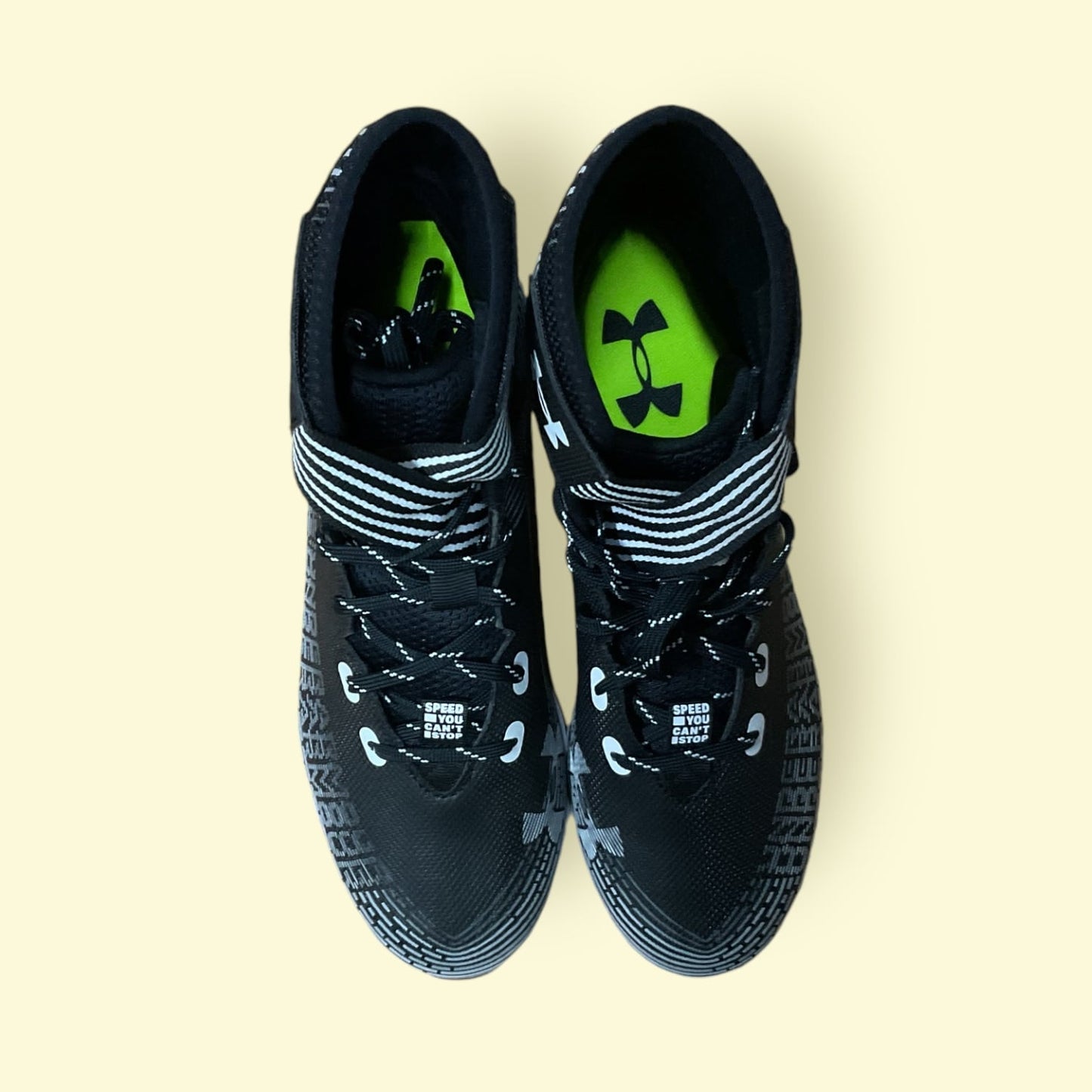 Tacos deportivos UA Highlight Franchise negros para béisbol y fútbol, con soporte en tobillo y suela de tracción.