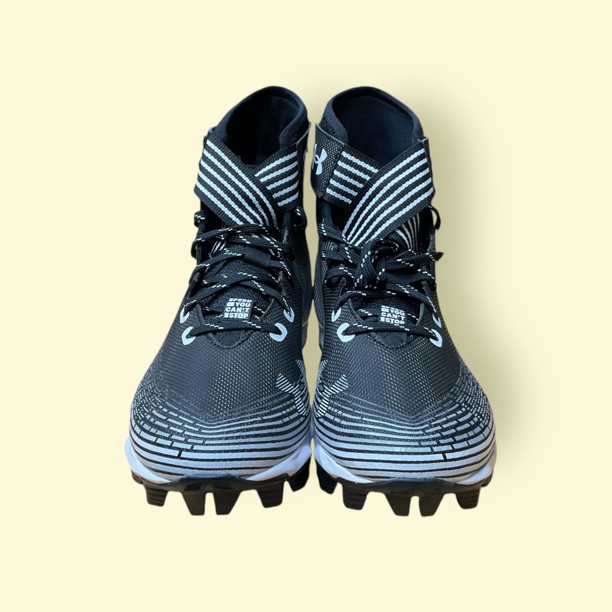 Tacos deportivos UA Highlight Franchise negros para béisbol y fútbol, con soporte en tobillo y suela de tracción.