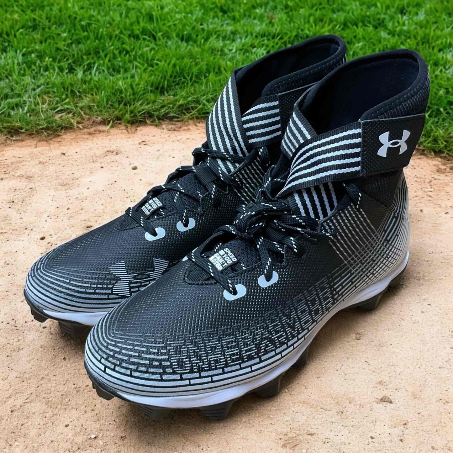 Tacos deportivos UA Highlight Franchise negros para béisbol y fútbol, con soporte en tobillo y suela de tracción.