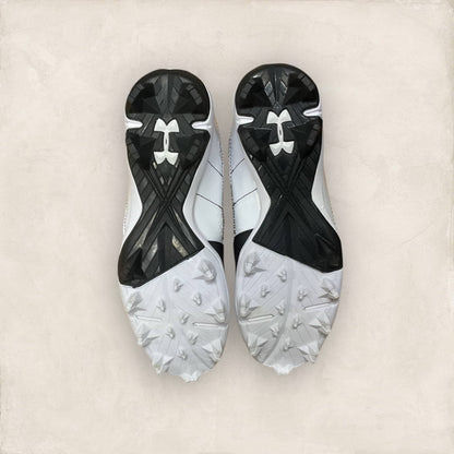 Zapatillas UA Harper 7 Mid RM Jr en negro y dorado, ideales para béisbol, con diseño moderno, parte superior ligera y suela de goma para un agarre superior.